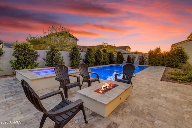 pool at dusk featuring a patio area, a fenced in pool, an outdoor fire pit, and a fenced backyard