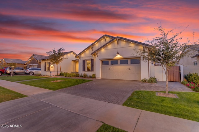 view of front of home with a lawn, decorative driveway, a garage, and stucco siding