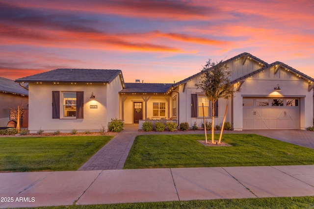 view of front of house with stucco siding, driveway, an attached garage, and a front yard