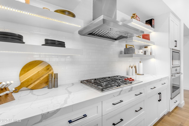 kitchen featuring open shelves, backsplash, white cabinetry, appliances with stainless steel finishes, and wall chimney range hood