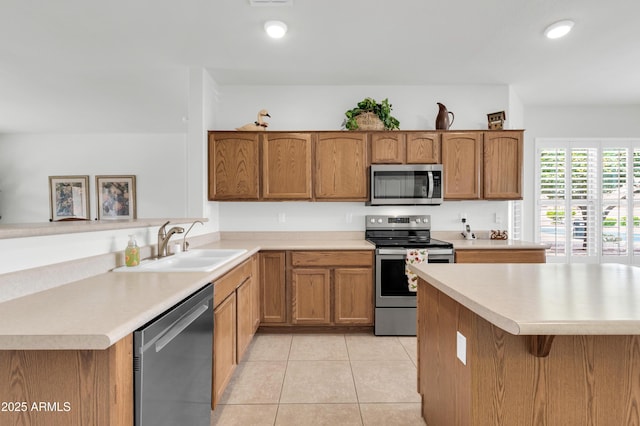 kitchen featuring light tile patterned floors, brown cabinets, appliances with stainless steel finishes, and a sink