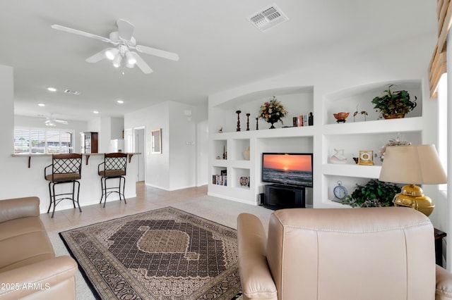 living room featuring built in features, visible vents, light tile patterned floors, and ceiling fan