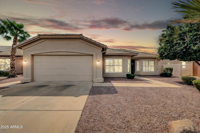 view of front of home featuring stucco siding, a tiled roof, an attached garage, and concrete driveway