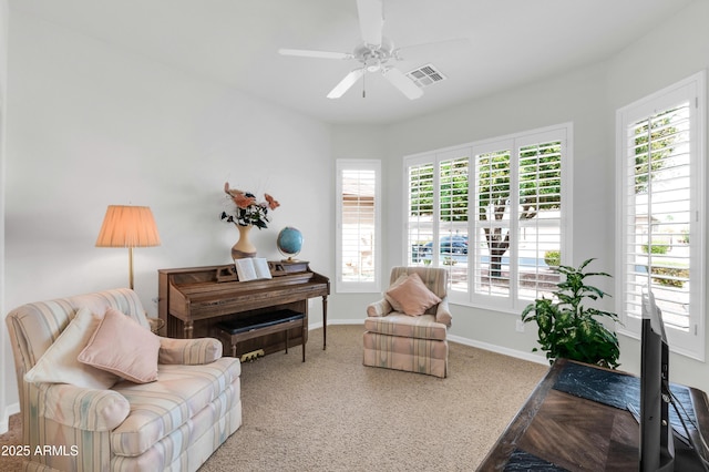 living room with visible vents, baseboards, and ceiling fan