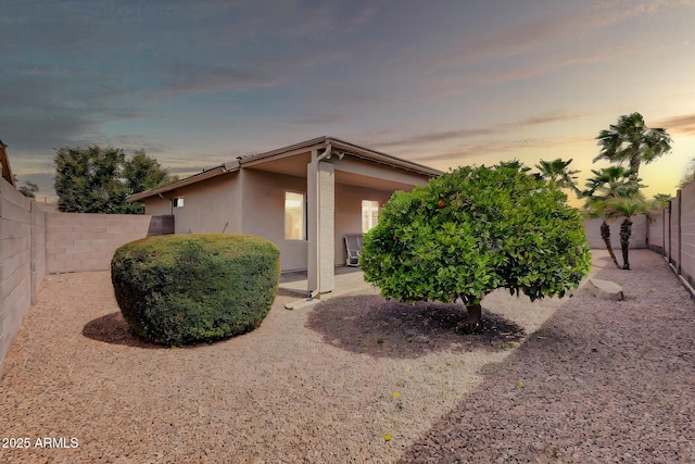 view of front facade with stucco siding, a fenced backyard, and a patio area