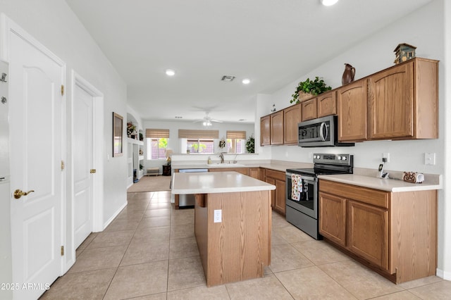 kitchen featuring light tile patterned floors, a peninsula, ceiling fan, stainless steel appliances, and light countertops