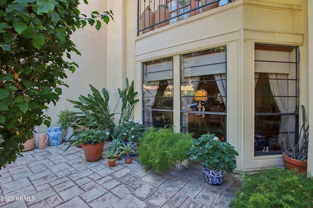 view of exterior entry featuring stucco siding, a patio, and a balcony