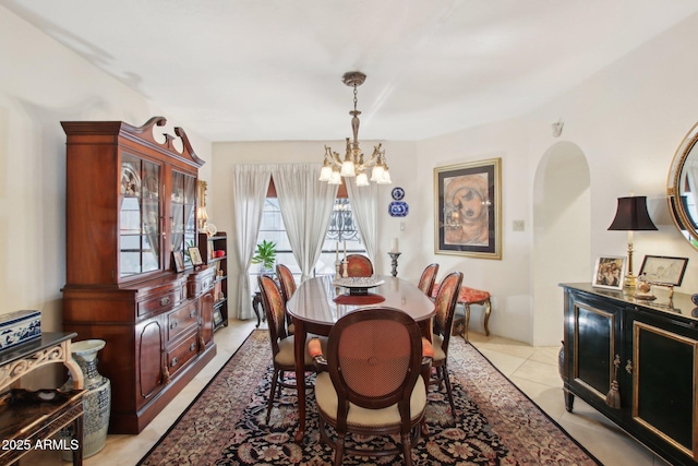 dining room featuring arched walkways, light tile patterned floors, and an inviting chandelier