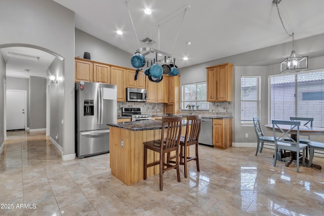 43271 W Little Dr, Maricopa, AZ 85138 - kitchen featuring stainless steel appliances, arched walkways, a kitchen island, baseboards, and tasteful backsplash