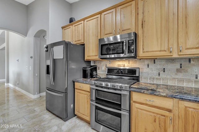 43271 W Little Dr, Maricopa, AZ 85138 - kitchen with dark stone countertops, arched walkways, appliances with stainless steel finishes, and tasteful backsplash