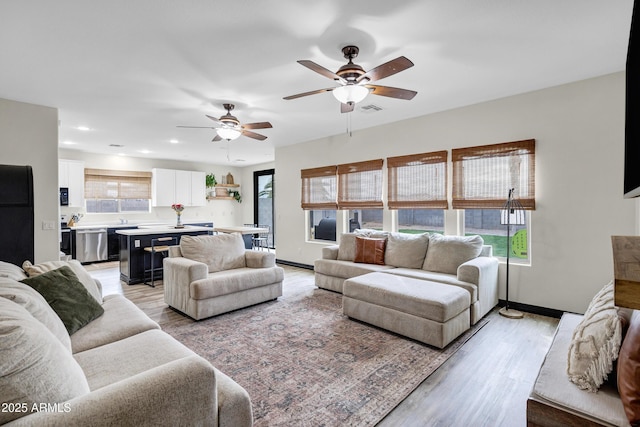 living room with ceiling fan and light wood-type flooring