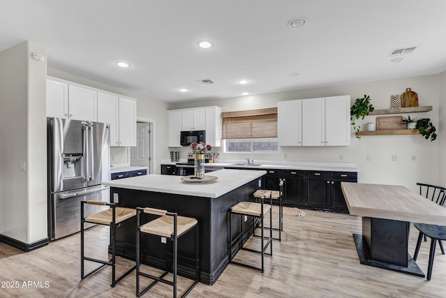 kitchen featuring white cabinetry, a kitchen island, a breakfast bar, and appliances with stainless steel finishes