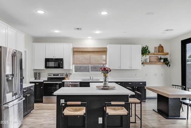 kitchen featuring white cabinetry, light hardwood / wood-style flooring, a center island, and appliances with stainless steel finishes