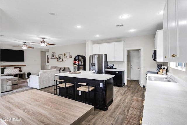 kitchen with high end fridge, sink, a center island, hardwood / wood-style flooring, and white cabinets