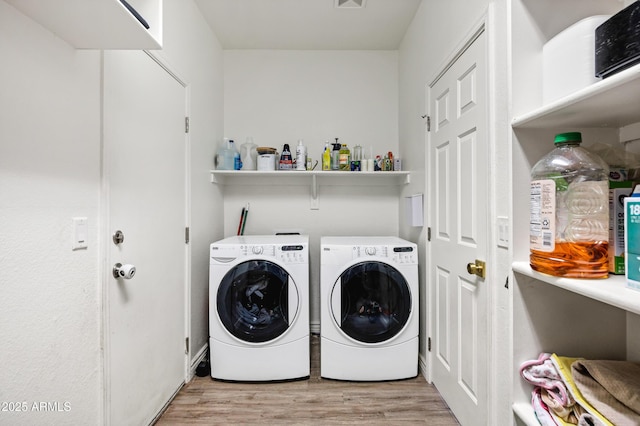 clothes washing area with washer and clothes dryer and light wood-type flooring