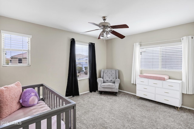 bedroom with ceiling fan, light colored carpet, and a crib