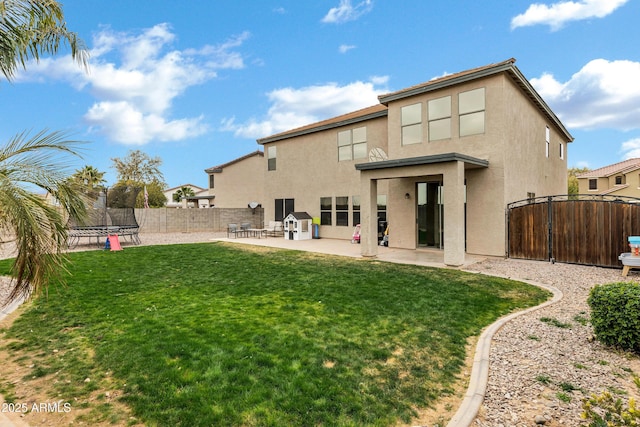 rear view of property featuring a patio, a yard, and a trampoline