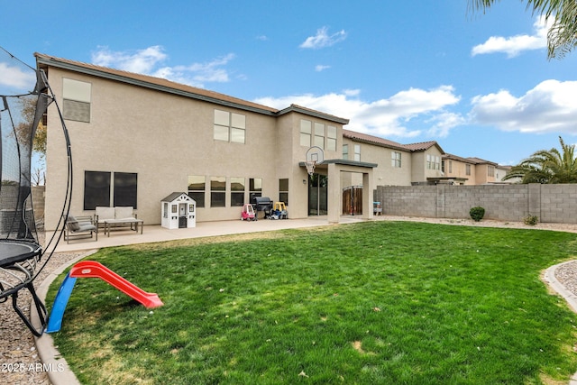 rear view of property with a patio, an outdoor hangout area, a yard, and a trampoline