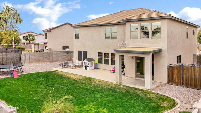 back of house with a yard, a trampoline, and a patio area