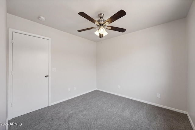 spare room featuring ceiling fan and dark colored carpet