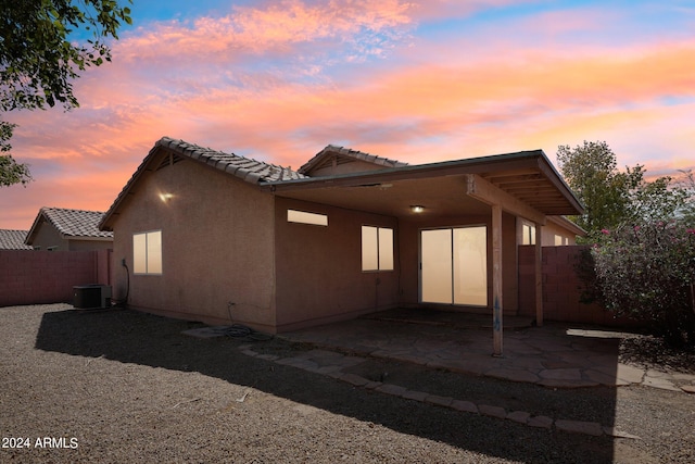 back house at dusk with a patio and cooling unit