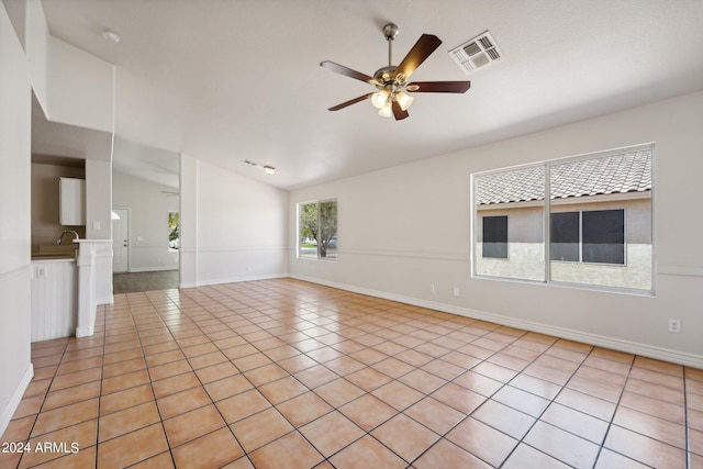 tiled empty room featuring vaulted ceiling, sink, and ceiling fan