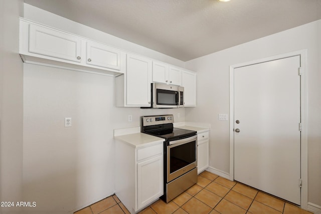 kitchen featuring a textured ceiling, stainless steel appliances, light tile patterned floors, and white cabinetry