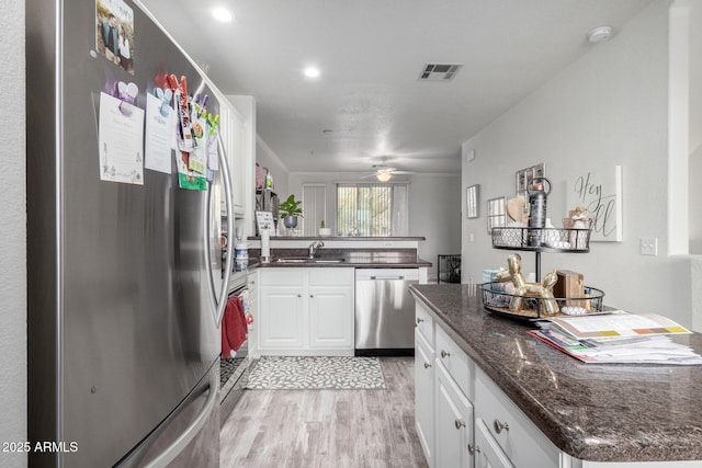 kitchen featuring stainless steel appliances, white cabinetry, sink, and light hardwood / wood-style floors