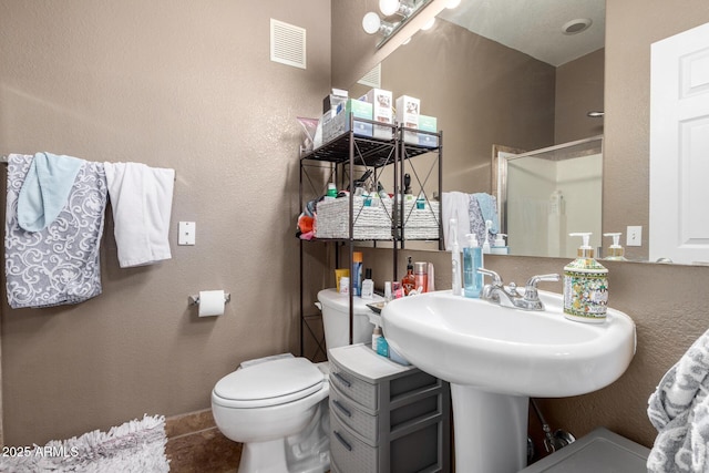 bathroom featuring toilet, sink, and a shower