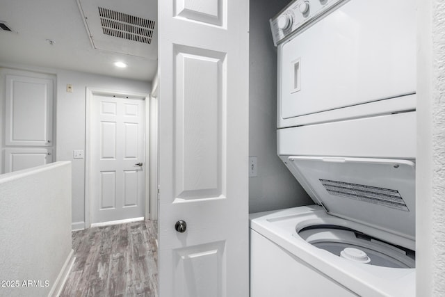 washroom featuring stacked washer / dryer and light hardwood / wood-style floors