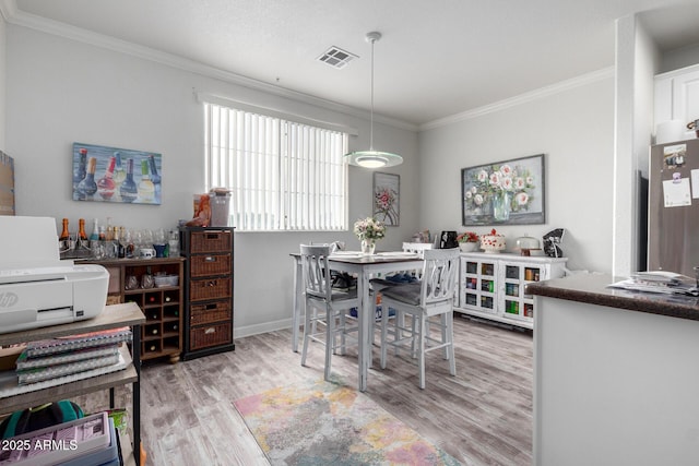 dining room featuring crown molding and light wood-type flooring