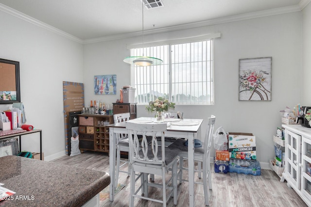 dining area with crown molding and light hardwood / wood-style flooring