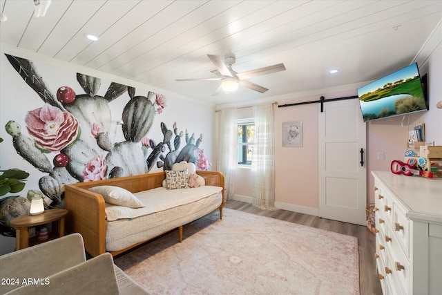 sitting room with wood ceiling, ceiling fan, crown molding, a barn door, and light hardwood / wood-style flooring