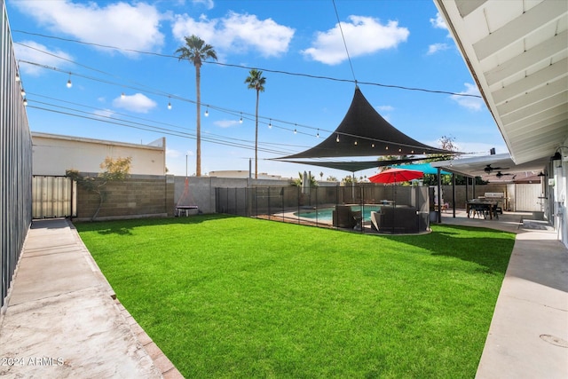 view of yard with a fenced in pool, ceiling fan, and a patio