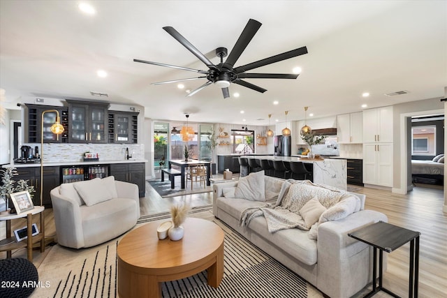 living room featuring ceiling fan, light hardwood / wood-style flooring, and sink