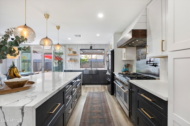 kitchen featuring pendant lighting, double oven range, premium range hood, tasteful backsplash, and white cabinetry