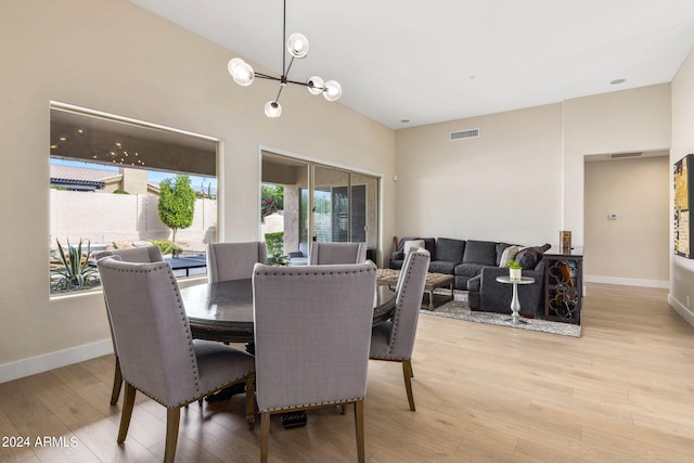 dining room featuring light wood finished floors, baseboards, visible vents, and an inviting chandelier