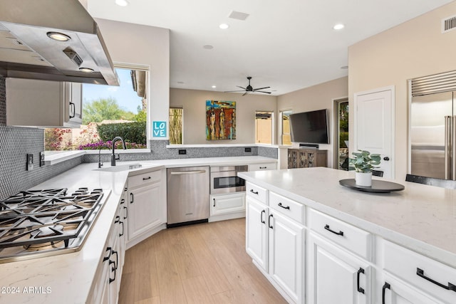 kitchen featuring white cabinetry, stainless steel appliances, under cabinet range hood, a sink, and a ceiling fan