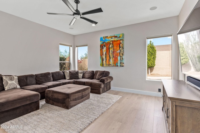 living room with light wood finished floors, baseboards, and ceiling fan