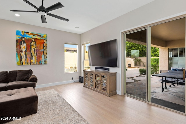 living area featuring baseboards, wood finished floors, a healthy amount of sunlight, and a ceiling fan