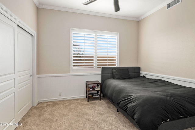 bedroom featuring light carpet, a closet, crown molding, and ceiling fan