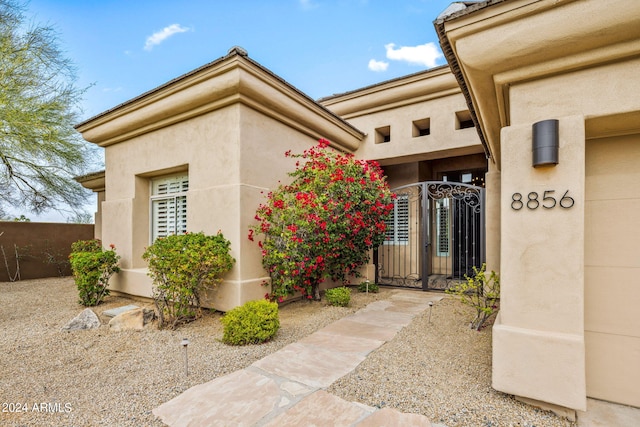 property entrance with a gate, fence, and stucco siding