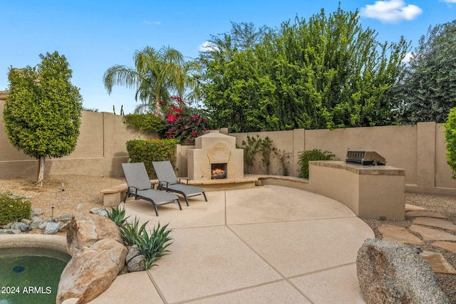 view of patio featuring a fenced backyard, area for grilling, and a lit fireplace