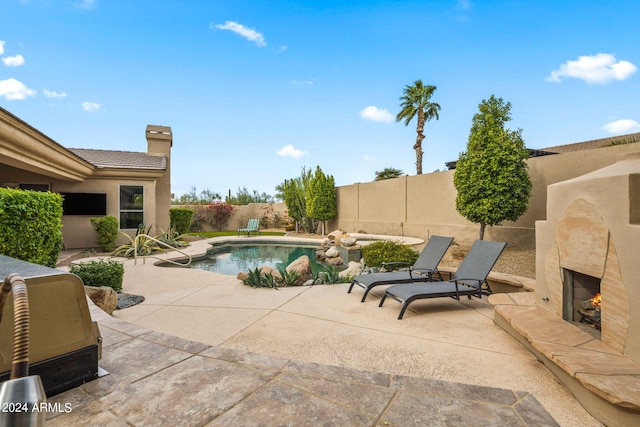 view of swimming pool with a patio and exterior fireplace