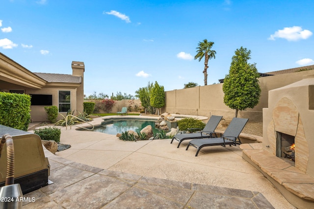 view of swimming pool with a warm lit fireplace, a fenced in pool, a fenced backyard, and a patio