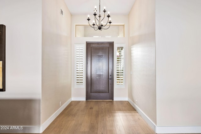 foyer entrance with wood-type flooring, visible vents, baseboards, and a chandelier