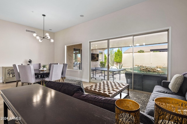 living room with baseboards, visible vents, wood finished floors, and an inviting chandelier