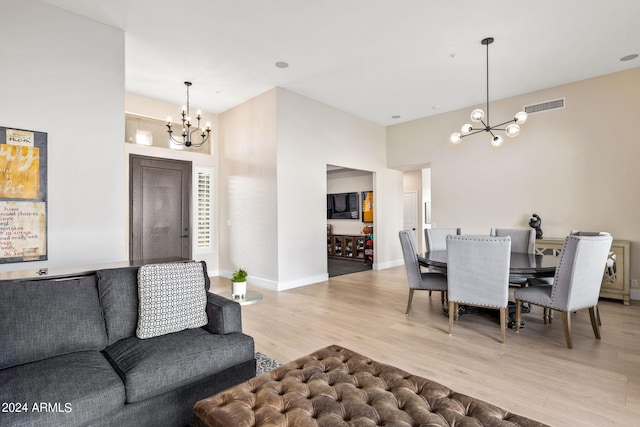 living area with baseboards, light wood-style flooring, visible vents, and a notable chandelier
