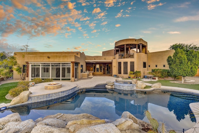 pool at dusk with an in ground hot tub, a patio area, and an outdoor fire pit