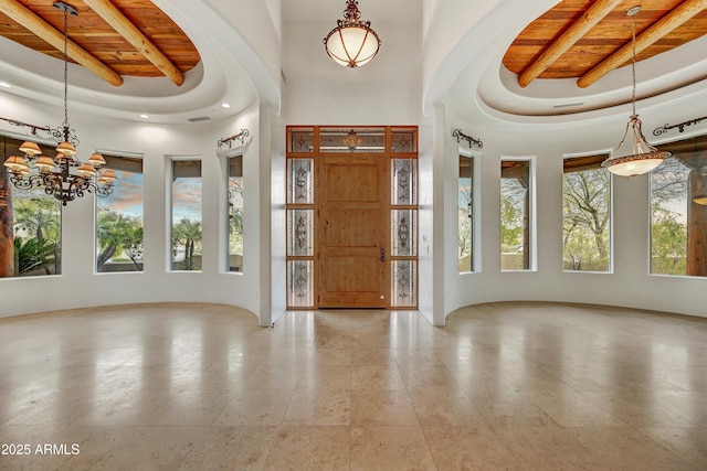 foyer entrance featuring a tray ceiling, beam ceiling, wooden ceiling, and a towering ceiling